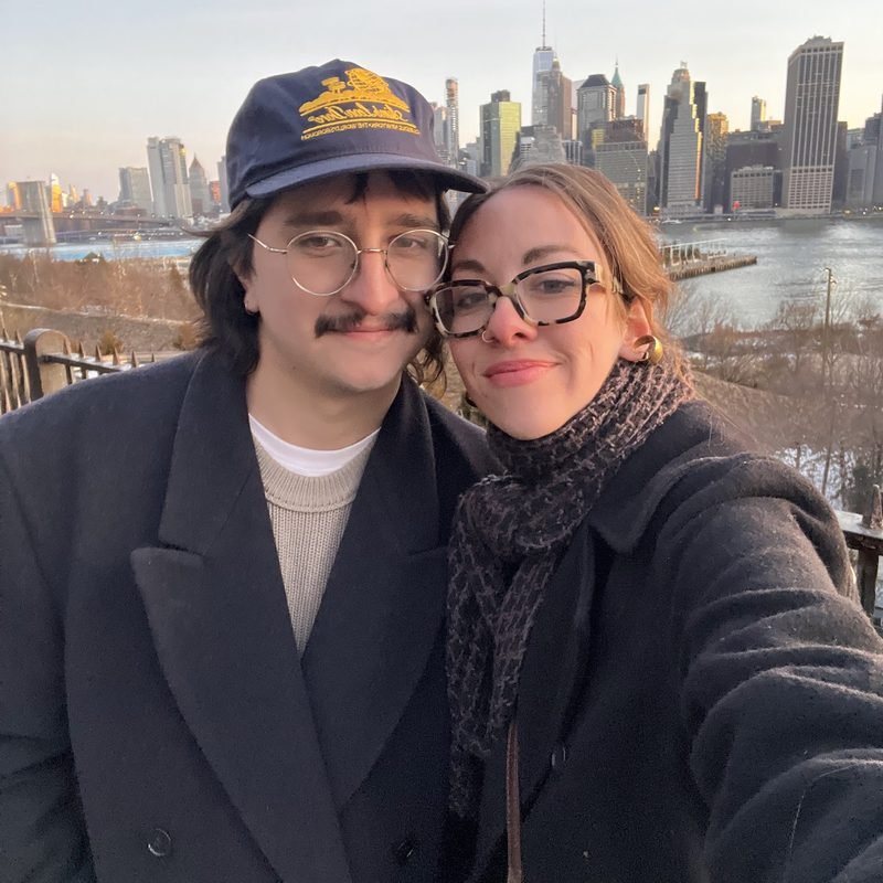 Simón and Tracy bundled up with the New York skyline behind them