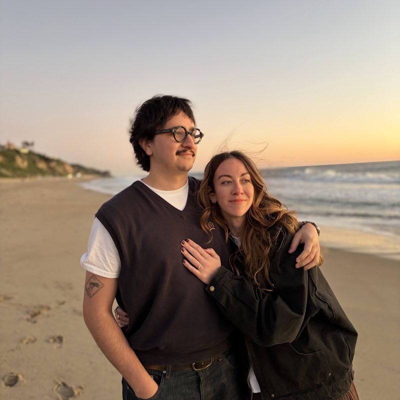 Simón and Tracy embracing on a beach at sunset