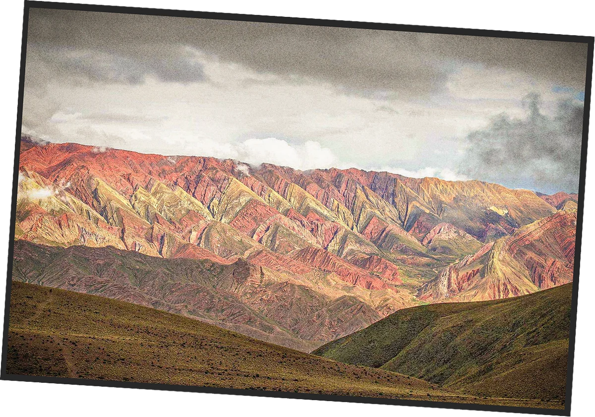 Postcard of red, ochre and green striped mountains under storm clouds in northwest Argentina