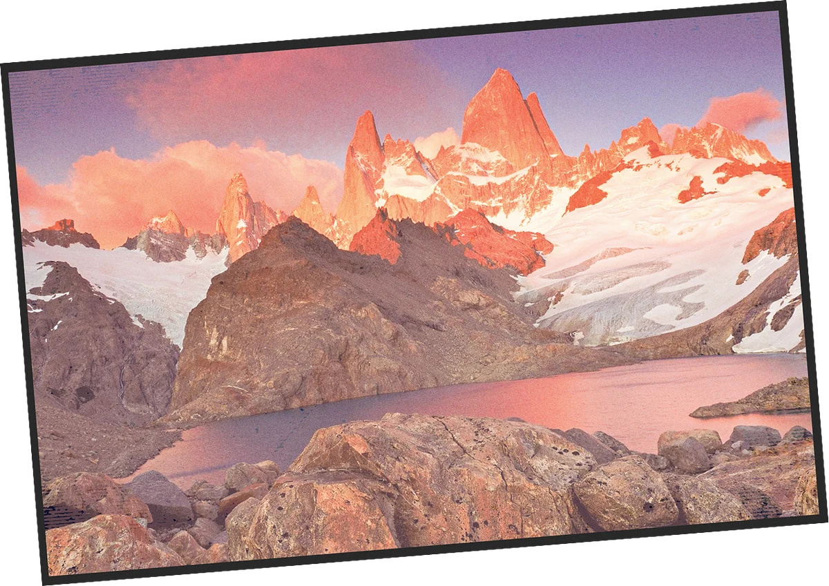 Postcard of jagged peaks glowing pink at sunrise above a mountain lake in Patagonia
